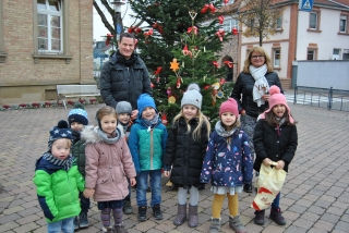 Kinder der Albert-Schweitzer-Kita vor dem geschmückten Rathaustannenbaum. Links hinten Hauptamtsleiter Jens Volpp, rechts hinten Bürgermeister-Stellvertreterin Annette Dietl-Faude.